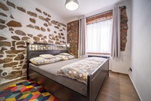 1 dormitorio con cama y pared de piedra en Apartmánový dům Jeník, en Nové Hrady
