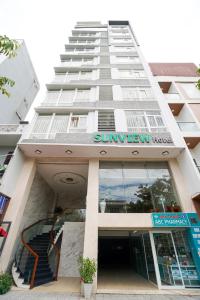 Un alto edificio bianco con un sole poco visibile di Sunview Beach Hotel Danang a Da Nang