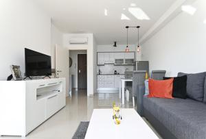 een woonkamer met een grijze bank en een keuken bij Apartment TRI MASLINE in Trogir