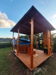 a man standing on a wooden deck with a gazebo at Pensiunea Casa Alex in Şarul Dornei