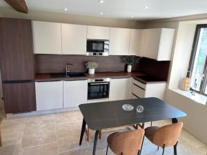 a kitchen with white cabinets and a black table and chairs at La maison de Mounette in LʼIsle-dʼAbeau