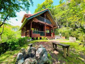 uma cabana de madeira com um banco à frente em Sunny Side Cottage em Shimoda