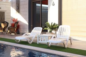 dos sillas blancas y una mesa junto a una piscina en شاليه ڤيو VIEW Chalet en Sowayma