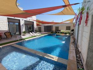 una piscina con sombrilla en el patio trasero en شاليه ڤيو VIEW Chalet, en Sowayma