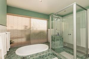 a bathroom with a glass shower and a white tub at Admiralty Bed & Breakfast in Muizenberg