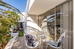 a patio with a table and chairs on a balcony at Admiralty Bed & Breakfast in Muizenberg