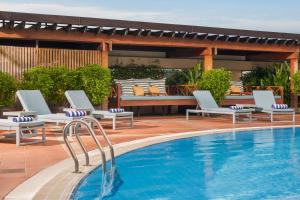 a pool with chaise lounge chairs next to a swimming pool at New World Saigon Hotel in Ho Chi Minh City