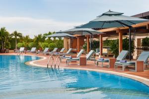 einen Pool mit Liegestühlen und Sonnenschirmen in der Unterkunft New World Saigon Hotel in Ho-Chi-Minh-Stadt