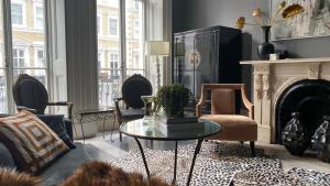 een woonkamer met een tafel en stoelen en een open haard bij South Ken designer pad in Londen