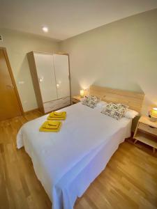 una camera da letto con un letto bianco e asciugamani gialli di El Rinconcito de Sabi a Sabiñánigo