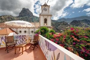 d'un balcon avec des chaises, une tour d'horloge et des fleurs. dans l'établissement Casa de Telégrafos, à Vallehermoso