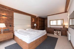 バンスコにあるFinest Luxury Penthouse Bansko Royal Towersの白い大型ベッドと木製の壁が備わるベッドルーム1室が備わります。