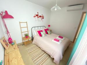 Schlafzimmer mit einem Bett mit rosa Kissen und einer Leiter in der Unterkunft BEACH & SUN MONCOFA in Moncófa