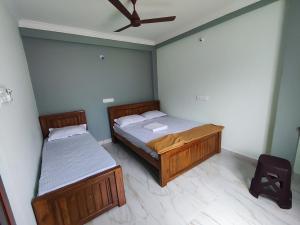 a bedroom with two beds and a ceiling fan at Sri Aksha Residency in Alāndurai
