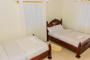 2 bedden in een kleine kamer met witte lakens bij Homely Escapes in Nanyuki
