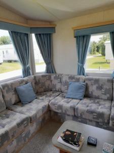 a living room with a couch with blue pillows at Lovely 8 Berth Caravan At Breydon Water Park, Nearby Norfolk Broads Ref 10111b in Belton