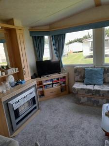 a living room with a television and a couch at Lovely 8 Berth Caravan At Breydon Water Park, Nearby Norfolk Broads Ref 10111b in Belton