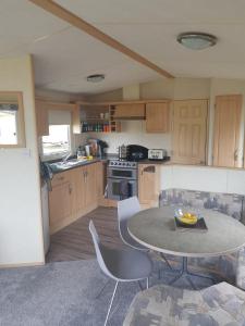 a kitchen with a table and chairs in a room at Lovely 8 Berth Caravan At Breydon Water Park, Nearby Norfolk Broads Ref 10111b in Belton
