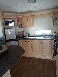 a kitchen with wooden cabinets and a white refrigerator at Lovely 8 Berth Caravan At Breydon Water Park, Nearby Norfolk Broads Ref 10111b in Belton