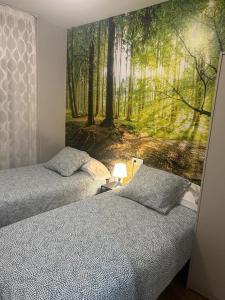 two beds in a bedroom with a mural of a forest at EL RAMILLETE in Soria