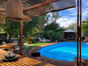 uma piscina num quintal com uma mesa de madeira em La Pension Guest House em Oudtshoorn