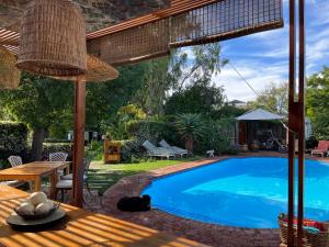 a swimming pool in a yard with a wooden table at La Pension Guest House in Oudtshoorn