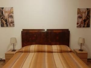a bedroom with a wooden bed with two lamps at San Nicolò House in Aci Catena