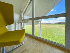 a yellow chair in a room with a large window at Familienunterkunft Wiesengeflüster S3 - kinderfreundlich, nur 3 Minuten zum Strand in Röbel