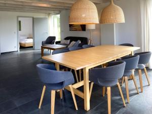 a dining room with a wooden table and blue chairs at Gruppenunterkunft Wiesengeflüster S2 mit Wiesenblick, Sauna und Kamin in Röbel