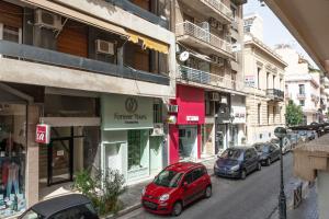 a red car parked on a street next to buildings at Praxitelous 141 City Apartment in Piraeus
