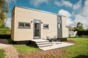 uma pequena casa com um alpendre, uma mesa e cadeiras em Tiny Om Ferienhaus em Laichingen