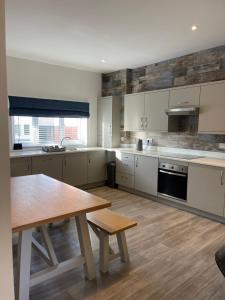 uma cozinha com armários brancos e uma mesa de madeira em Oyster Retreat em Amble