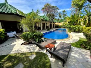 a backyard with a pool and chairs and a house at 1 BR Balinese Villa In The Heart of Sanur in Sanur