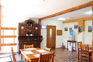 a dining room with a table and a grandfather clock at Pensiunea Bendorfeanu in Răşinari