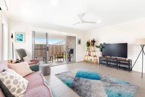 a living room with a couch and a flat screen tv at 'The Pool House' Spacious Family Stay at Hervey Bay in Urraween