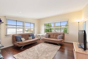 een woonkamer met 2 banken en een flatscreen-tv bij Coastal Queenslander with Fraser Island Views in Boonooroo