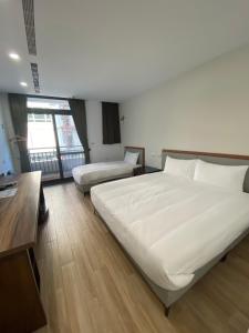 a hotel room with two beds and a desk at 浯島文旅WD Hotel in Jinhu