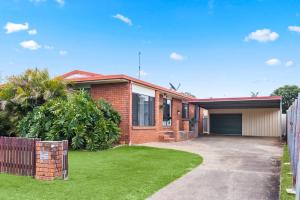 a brick house with a driveway and a fence at 'The Aussie Classic' Poolside Living by the Marina in Urangan