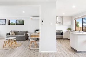 a white living room with a couch and a table at 'The Aussie Classic' Poolside Living by the Marina in Urangan