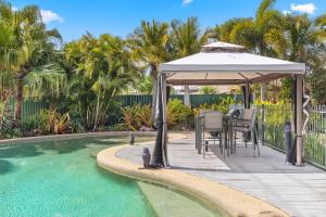 un patio con mesa y cenador junto a la piscina en Private Resort-style Queenslander at Hervey Bay en Urangan