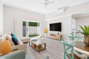 a living room with a couch and a tv at 'Esplanade Escape' A Fresh Coastal Family Hideaway in Urangan