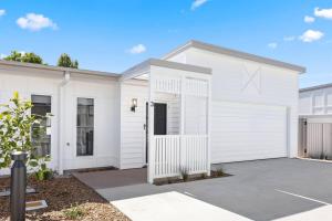 a white house with a garage at 'Esplanade Escape' A Fresh Coastal Family Hideaway in Urangan