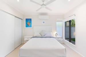 a white bedroom with a bed and a window at Luxe By The Marina - Hamptons Chic at Hervey Bay in Urangan