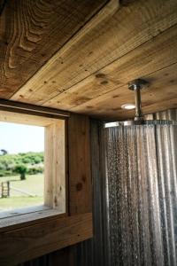 a wooden ceiling with a shower curtain and a window at Glamping at Macdonald's Farm in Saint Ervan