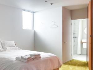 Akizuki OKO art&inn في Asakura: غرفة نوم بسرير ابيض عليها مناشف