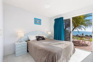 a bedroom with a bed and a view of the ocean at Sandy Straits Poolside Escape with Beach Access in Hervey Bay
