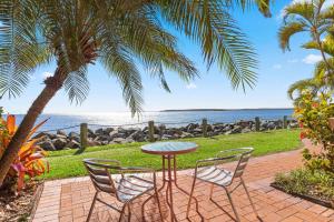 a table and chairs with a view of the ocean at Sandy Straits Poolside Escape with Beach Access in Hervey Bay