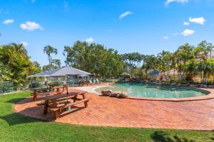 a pool with a picnic table and benches in a park at Sandy Straits Poolside Escape with Beach Access in Hervey Bay