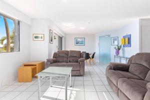 a living room with couches and a table at Sandy Straits Poolside Escape with Beach Access in Hervey Bay