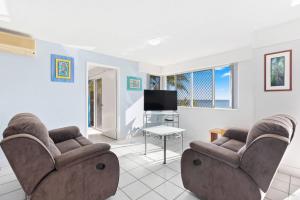 a living room with two chairs and a flat screen tv at Sandy Straits Poolside Escape with Beach Access in Hervey Bay